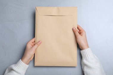 Gri masadaki Kraft kağıt zarflı kadın, üst manzara.