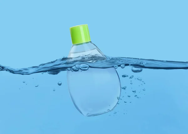 Flaska Med Babyolja Flyter Vatten Mot Ljusblå Bakgrund — Stockfoto