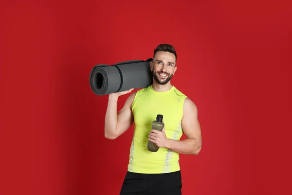 Bonito Homem Com Tapete Ioga Garrafa Água Fundo Vermelho — Fotografia de Stock