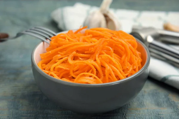 Delicious Korean carrot salad in bowl on blue wooden table