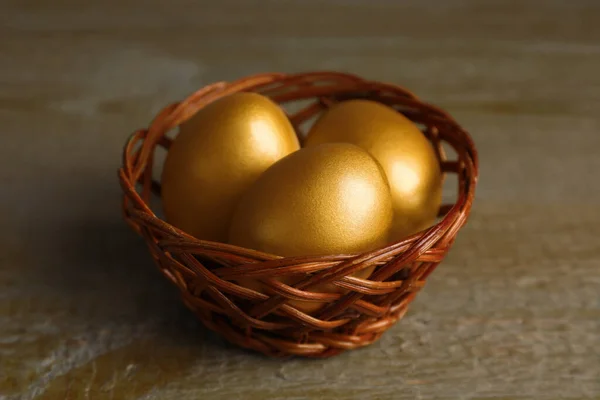 Rieten Mand Met Gouden Eieren Houten Tafel Close — Stockfoto