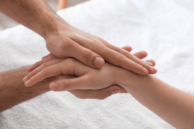Kadın yumuşak havluyla el masajı yaptırıyor, yakın plan.