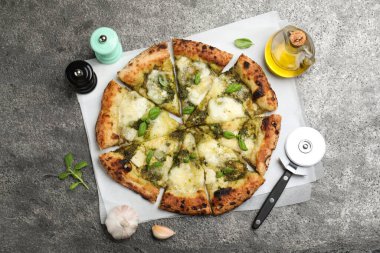 Gri masada servis edilen pesto, peynir ve fesleğenli lezzetli pizza.