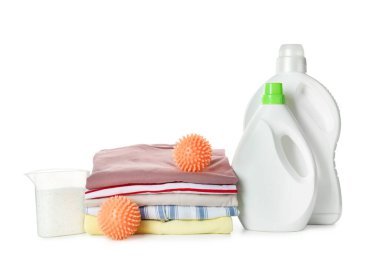 Turuncu kurutucu topları, deterjanlar ve temiz giysiler beyaz arka planda.