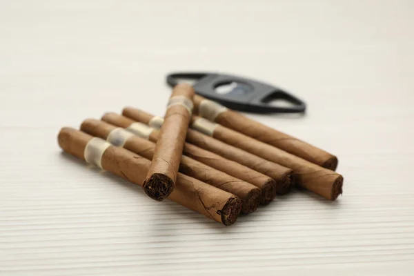 白色木制桌子上的雪茄和断头台刀具 — 图库照片