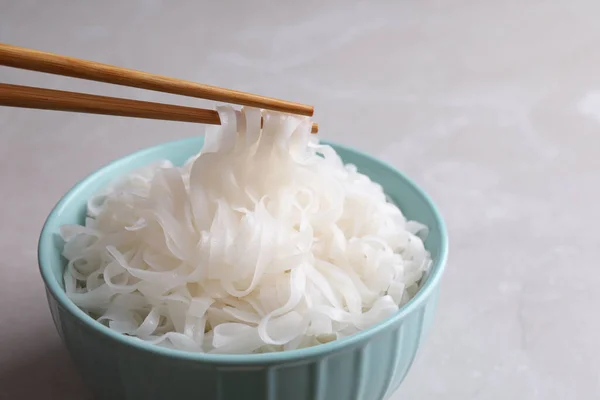 Taking Rice Noodles Chopsticks Bowl Light Grey Table Closeup — Stock Photo, Image