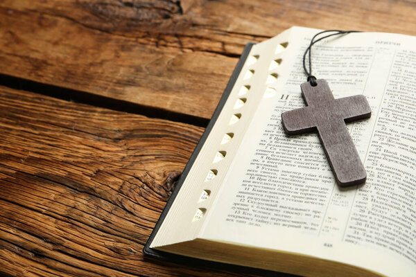 MYKOLAIV, UKRAINE - DECEMBER 20, 2021: Christian cross and Bible on wooden table, space for text