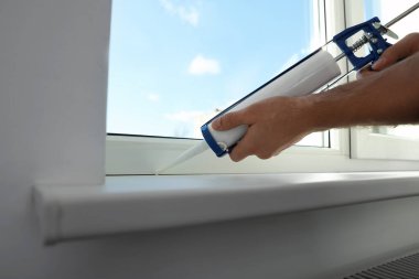 Caulk ile pencereyi kapatan adam, yakın plan.