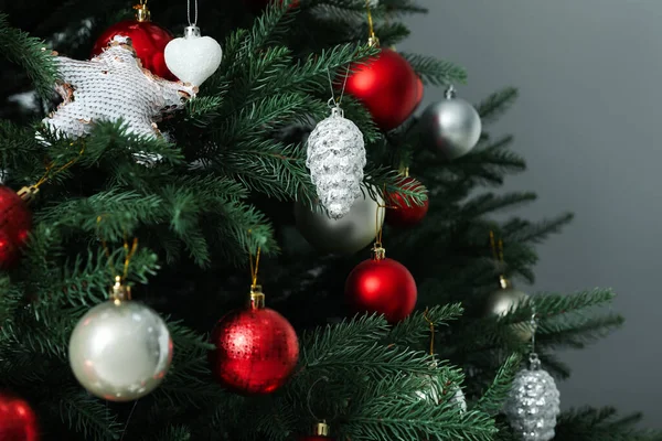 Gri arka planda güzel dekore edilmiş Noel ağacı, yakın plan.