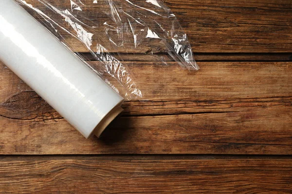 Roll of plastic stretch wrap film on wooden table, top view. Space for text