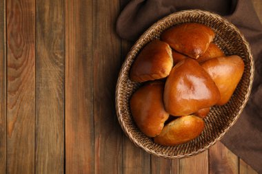 Hasır sepet ve lezzetli pirozhki ahşap masada, düz yatıyordu. Metin için boşluk