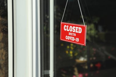 Camda asılı duran Covid-19 nedeniyle kapalı olan kırmızı tabela. Coronavirus karantinası