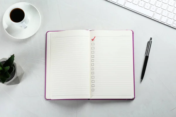 Cuaderno Con Casillas Verificación Taza Café Planta Sobre Mesa Blanca — Foto de Stock