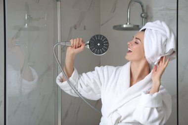 Genç ve güzel bir kadın banyoda şarkı söylüyor.