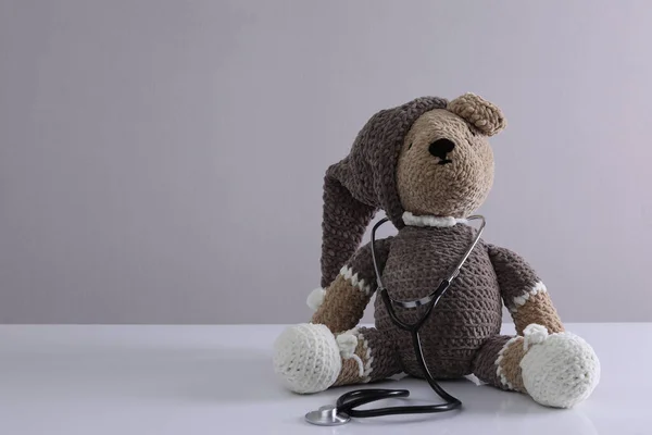 Leksaksbjörn Med Stetoskop Vitt Bord Mot Ljusgrå Bakgrund Utrymme För — Stockfoto