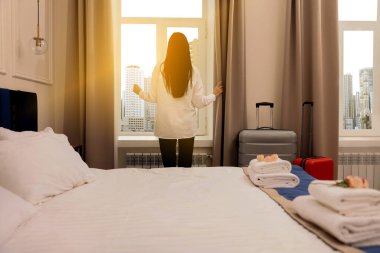 Otel odasındaki pencerenin yanında genç bir kadın.