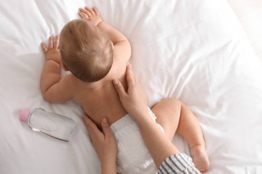 Anne, tatlı bebeğine masaj yapıyor. Yatakta yağlı, yakın plan.
