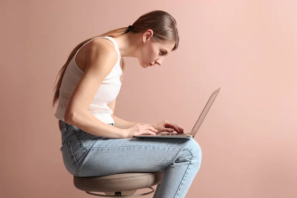 Kobieta Złą Postawą Przy Użyciu Laptopa Podczas Siedzenia Stołku Bladoróżowym — Zdjęcie stockowe