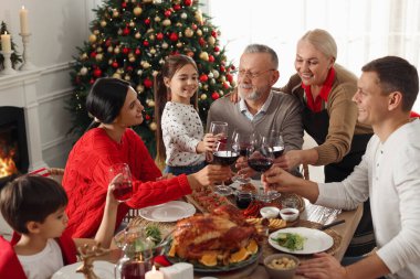 Mutlu aile şenlikli akşam yemeğinde bardaklarını tokuşturur. Noel kutlaması