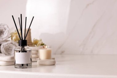 Aromatik kamış oda spreyi ve spa taşları beyaz masada, metin için yer