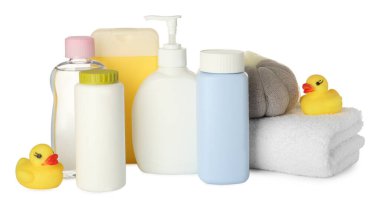 Beyaz arka planda bebek kozmetik ürünleri, havlu, banyo süngeri ve lastik ördekler.
