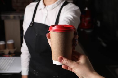 Barista, kahveli paket kâğıt bardağı müşteriye veriyor, yakın plan.