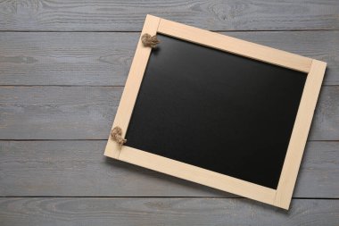 Gri ahşap masadaki temiz, küçük siyah karatahta, üst manzara. Metin için boşluk