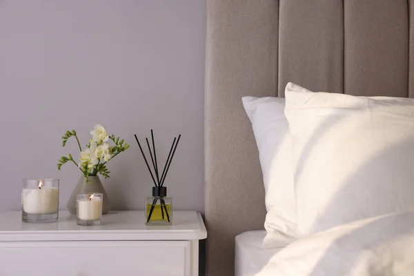 芳香のある葦の空気の新鮮さ 寝室の白いベッドサイドテーブルの上のフリージアの花やキャンドル — ストック写真