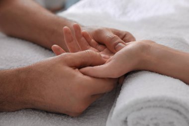 Kadın yumuşak havluyla el masajı yaptırıyor, yakın plan.