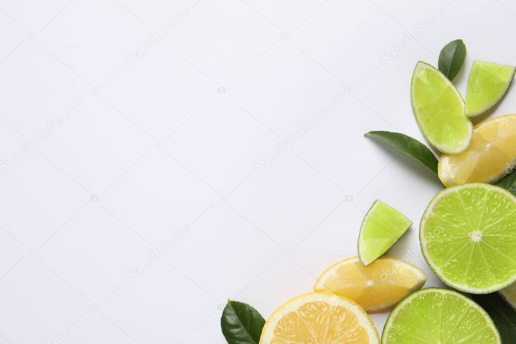 Fresh ripe lemons, limes and green leaves on white background, top view