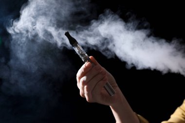 Siyah arka planda elektronik sigara tutan kadın, yakın plan.