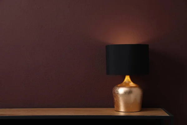 部屋の茶色の壁の近くのランプと木製のテーブル テキストのためのスペース — ストック写真