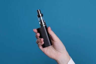 Açık mavi arka planda elektronik sigara tutan kadın, yakın plan.