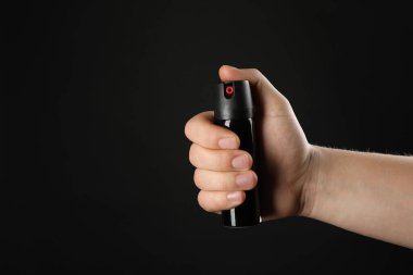 Siyah arka planda biber gazı tutan adam, yakın plan. Metin için boşluk