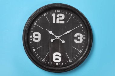 Açık mavi duvarda asılı şık analog saat