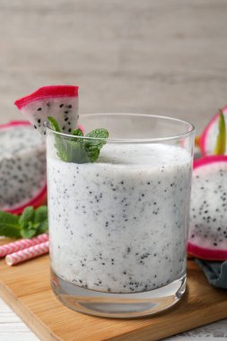 Bir bardak lezzetli pitahaya smoothie beyaz ahşap masa üzerinde taze nane, yakın plan