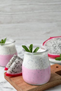 Lezzetli pitahaya smoothie, meyveler ve beyaz mermer masada taze nane.