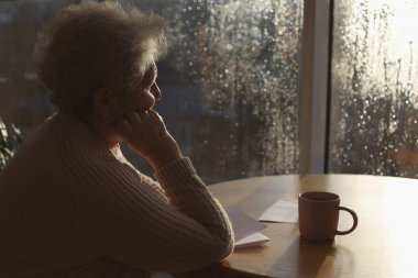 Yağmurlu bir günde içkili yaşlı bir kadın pencereden dışarı bakıyor, mesaj için yer var. Yalnızlık kavramı