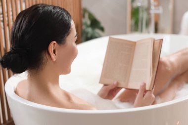 Güzel genç kadın alarak banyo evde kitabı okuma