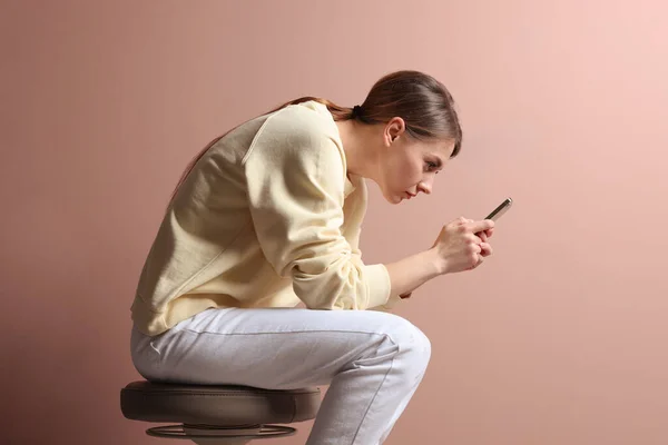 Mulher Com Postura Usando Smartphone Enquanto Sentado Fezes Contra Fundo — Fotografia de Stock