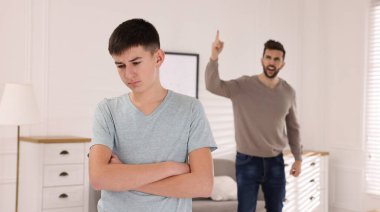 Baba oğlunu evde azarlıyor. Gençlik sorunları