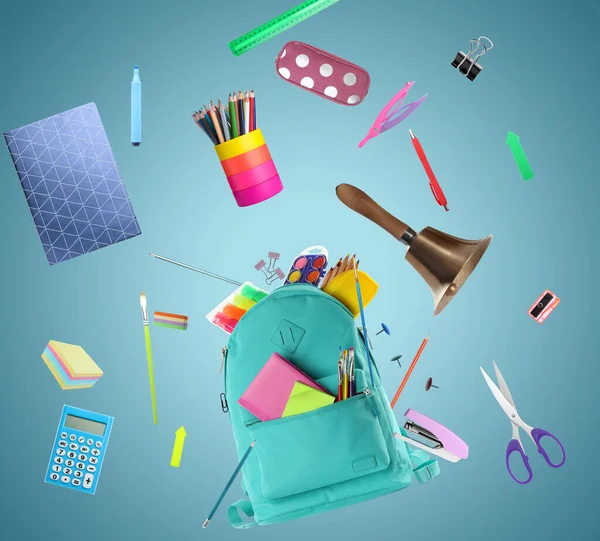 Turquoise backpack, school bell and different stationery flying on light blue background