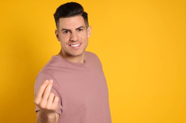 Sarı arka planda parmaklarını şaklatan yakışıklı bir adam. Metin için boşluk