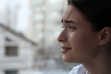 İçerideki pencerenin yanında ağlayan üzgün genç kadın, mesaj için yeri olan yakın plan. Yalnızlık kavramı