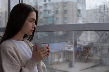Melankolik genç kadın yağmurlu bir günde pencereden dışarı bakıyor, mesaj için yer var. Yalnızlık kavramı