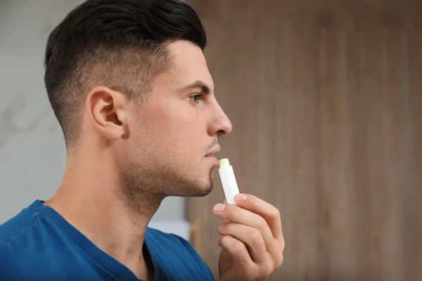 Schöner Mann Anwendung Hygienischer Lippenbalsam Innenräumen — Stockfoto