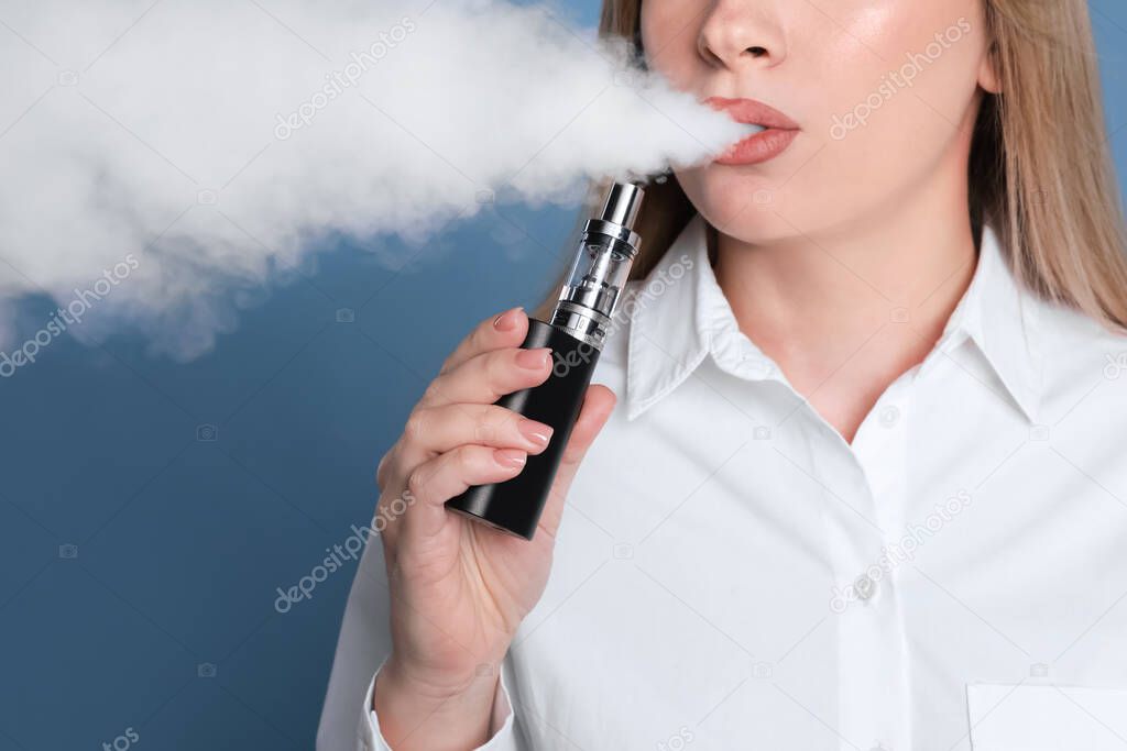 Young woman using electronic cigarette on light blue background, closeup