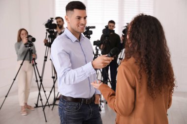 Profesyonel gazeteci, Afrikalı Amerikalı genç bir kadınla içeride röportaj yapıyor.