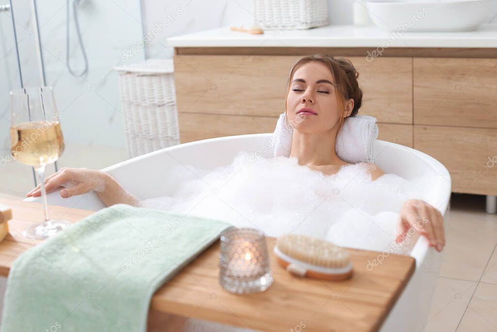 Beautiful woman enjoying bubble bath at home