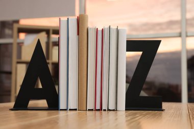 Minimalist letter bookends with books on wooden table indoors clipart